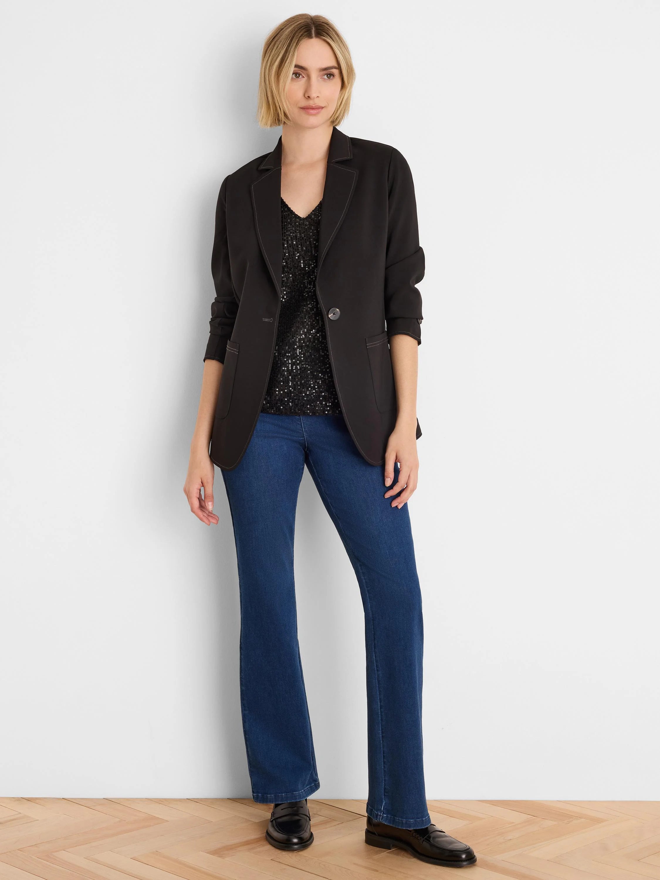Black blazer with light accent stitching on lapels, front, pockets, and cuffs. Features a single gray button.
