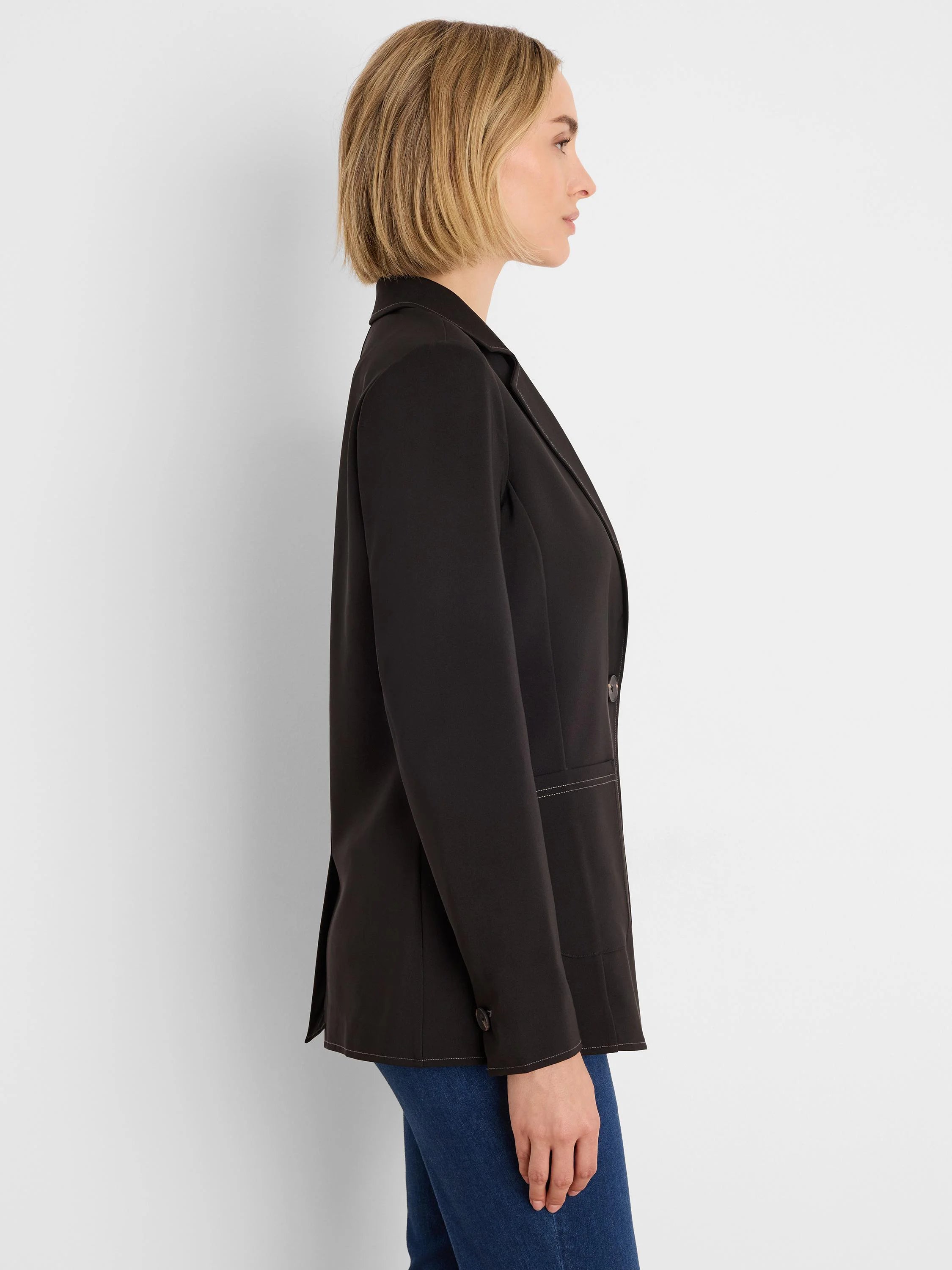 Black blazer with contrasting light accent stitching on lapels, pockets, and hem. Single front button, cuff buttons.