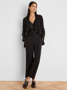 Black blazer with light accent stitching on lapels & seams. Model wears it with a black sequin top & trousers.
