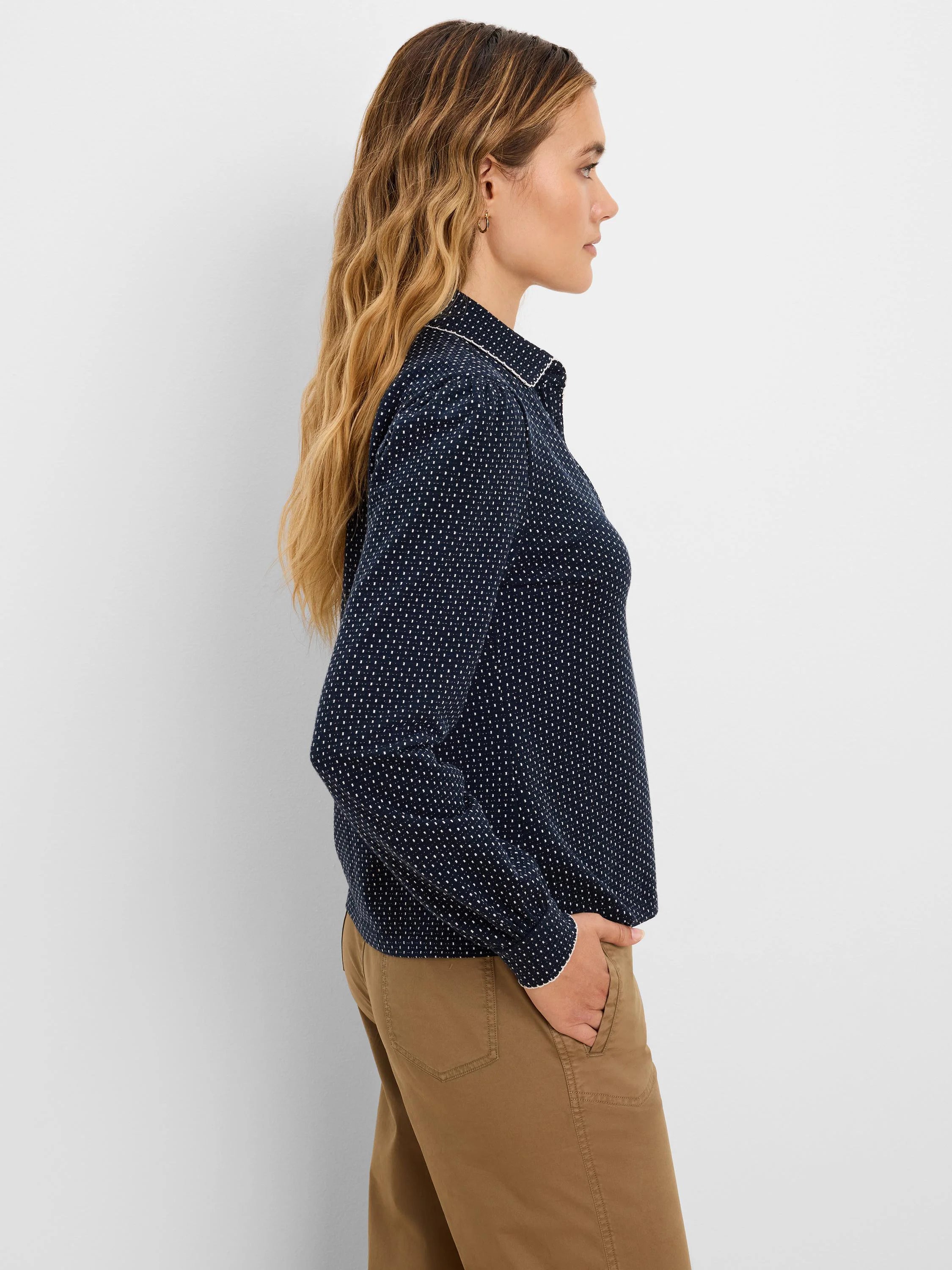Navy blue polo top with a small white dot pattern, featuring white trim on the collar and cuffs.