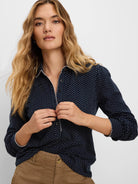 Navy collared top with small white square dots, and white contrast trim on the button placket and cuffs.
