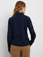 Navy blue eyelet top with collar and long sleeves. Features a pattern of small, leaf-shaped cutouts.