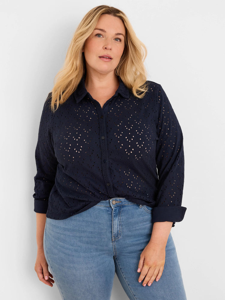 Navy blue eyelet top with small circular cut-outs. Features a collar, buttons, rolled sleeves, and a knotted hem.