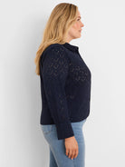 Navy blue eyelet knit top with collar and long sleeves, featuring small cutouts.