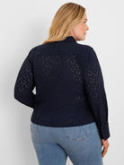 Navy blue eyelet top on model, viewed from back. Features long sleeves, a collar, and small scalloped holes throughout.