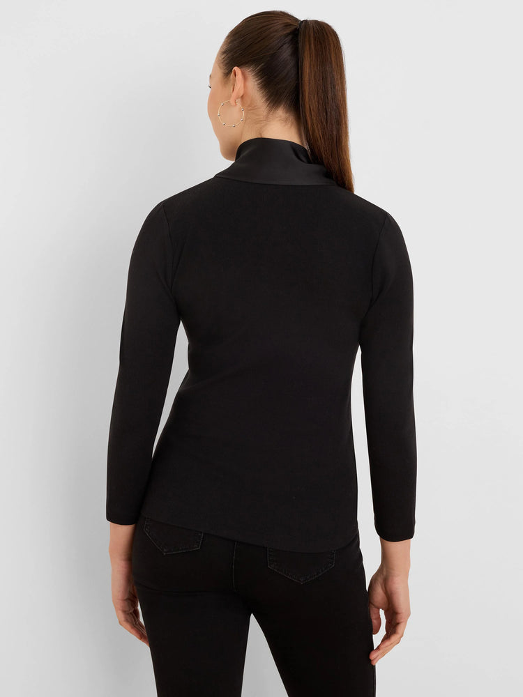 Black ribbed long-sleeve top with a high, smooth mock-neck collar, seen from behind.