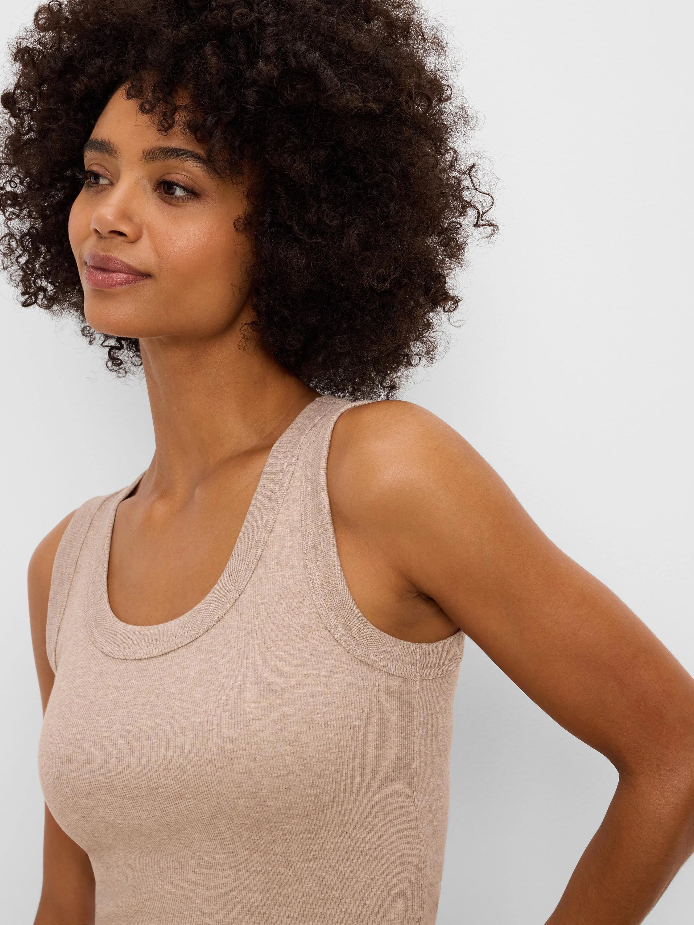 Light beige ribbed knit tank with a scoop neck, wide straps, and a form-fitting cut.