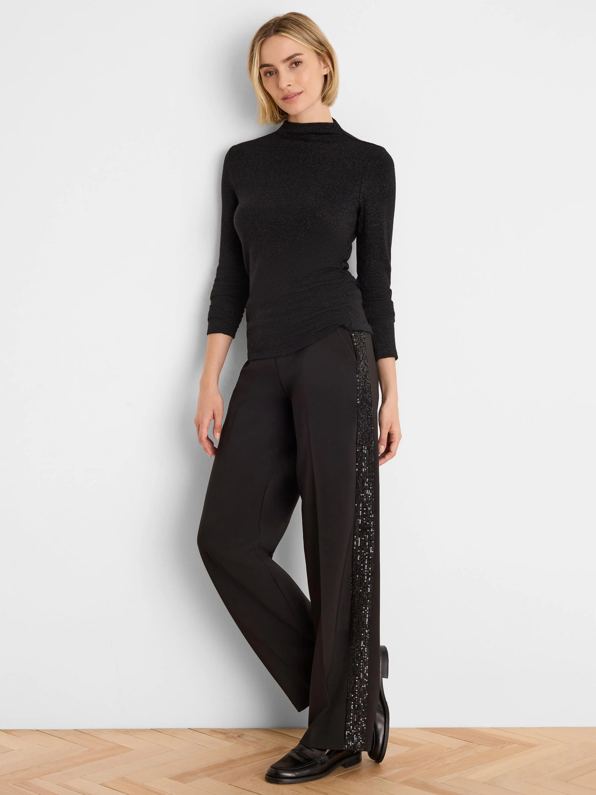 Black mock neck top with 3/4 sleeves, subtle sparkle, and a ruched side detail.