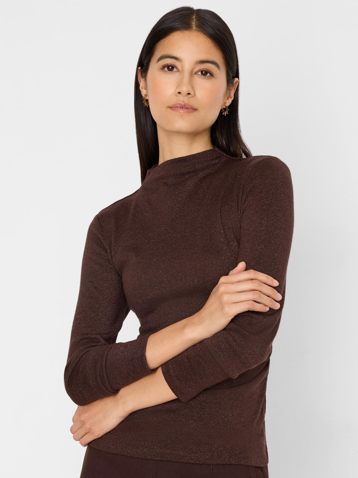 Model wears a dark brown, shimmering mock-neck long-sleeve top.