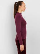 Woman wearing a shimmering plum long-sleeve mock neck top in profile.