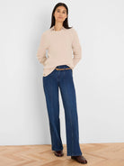 Light beige waffle knit top with a round neck, long sleeves, and gold side buttons along the left hem.