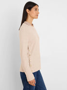 Light beige waffle knit top with a crew neck, long sleeves, and five round gold buttons down the left side.