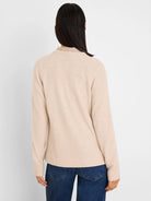 Back view of a model in a light beige waffle knit top with long raglan sleeves and a mock neck.
