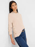 Pale beige waffle knit top with long sleeves. Gold buttons align the left side seam.