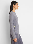 Light grey waffle knit top with long sleeves. Four gold buttons run vertically on the left side seam.