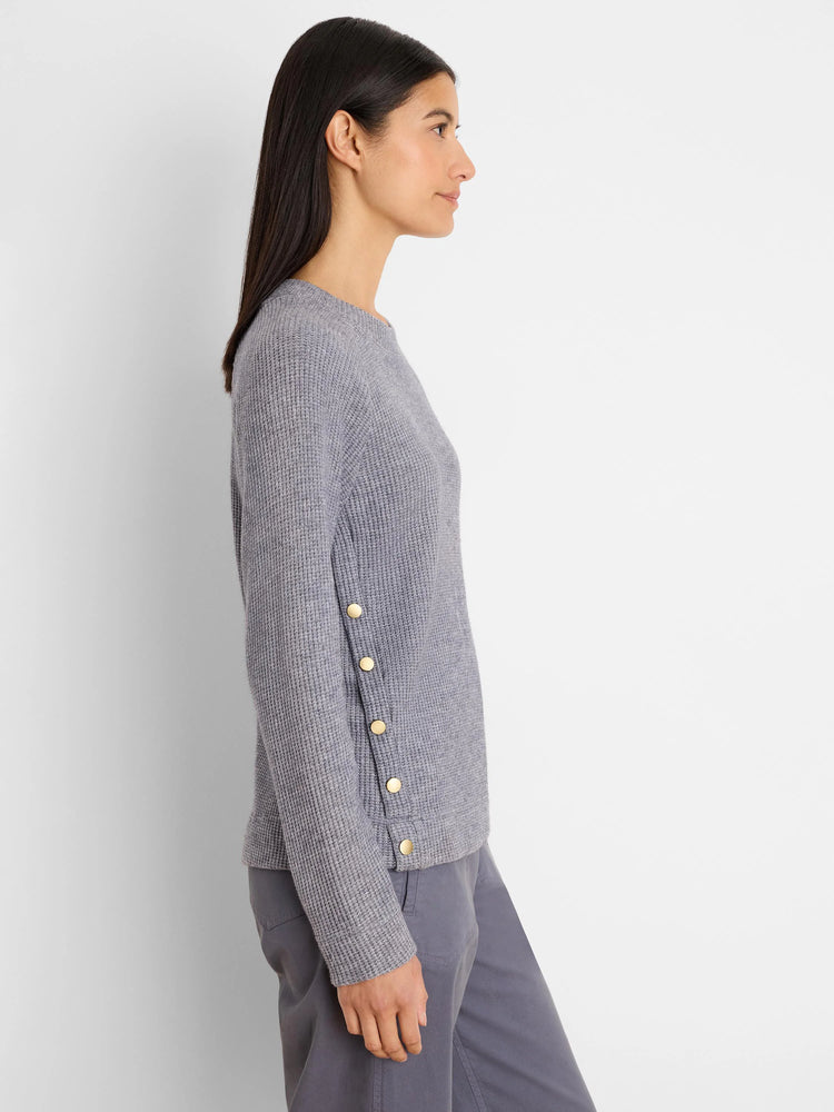 Light grey waffle knit top with long sleeves. Four gold buttons run vertically on the left side seam.
