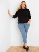 Black waffle knit top with long sleeves and six gold buttons running vertically down the left side.