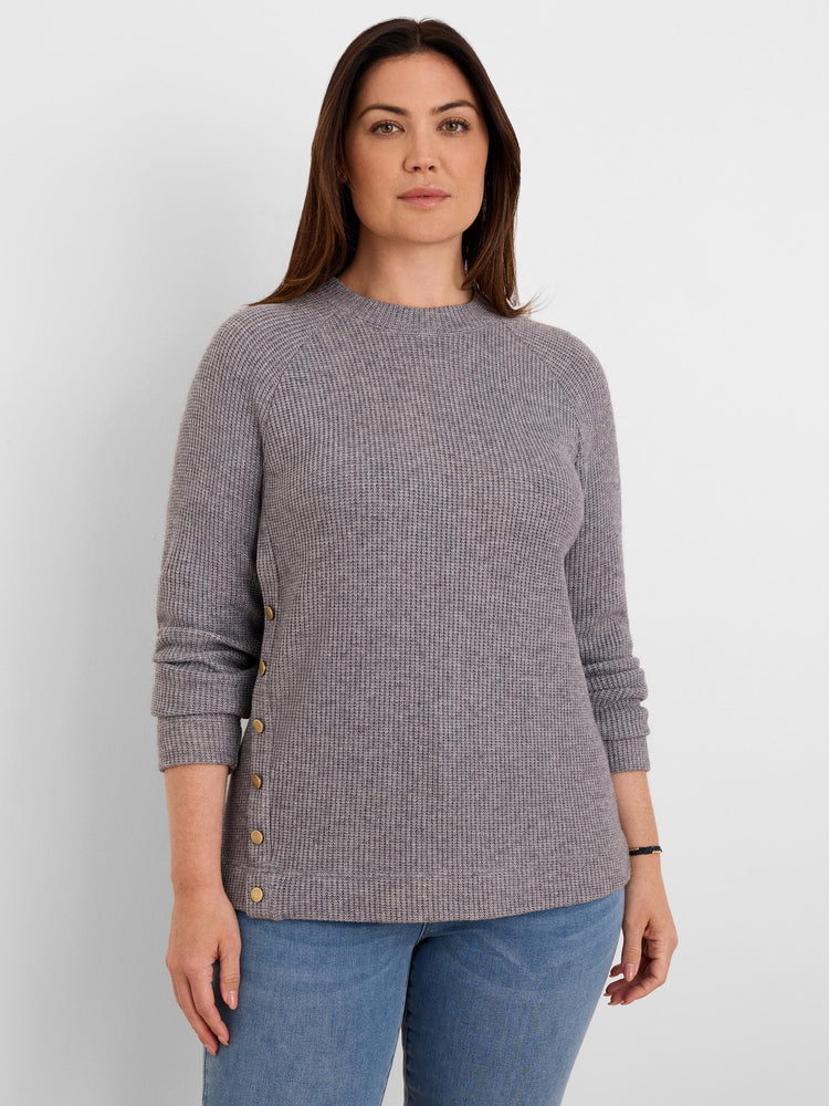 Grey waffle knit top with a crew neck, long sleeves, and brass buttons running down one side.