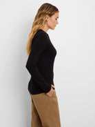 Black crinkle knit long-sleeve top, showing its textured pattern. Model wears it with tan pants.