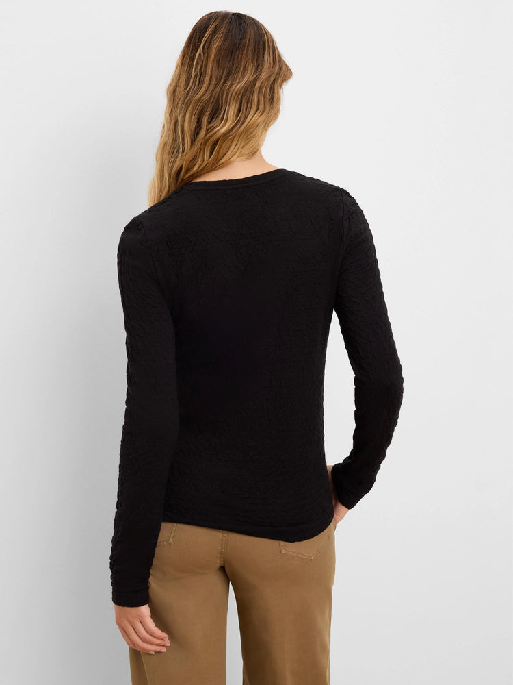 Black long-sleeved top featuring a distinct crinkle knit texture, worn by a woman from behind.