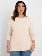 Pale beige, long-sleeve crinkle knit textured top with a round neckline.