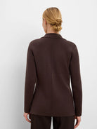 Dark brown knit blazer with a collar and center back seam, worn by a woman facing away.