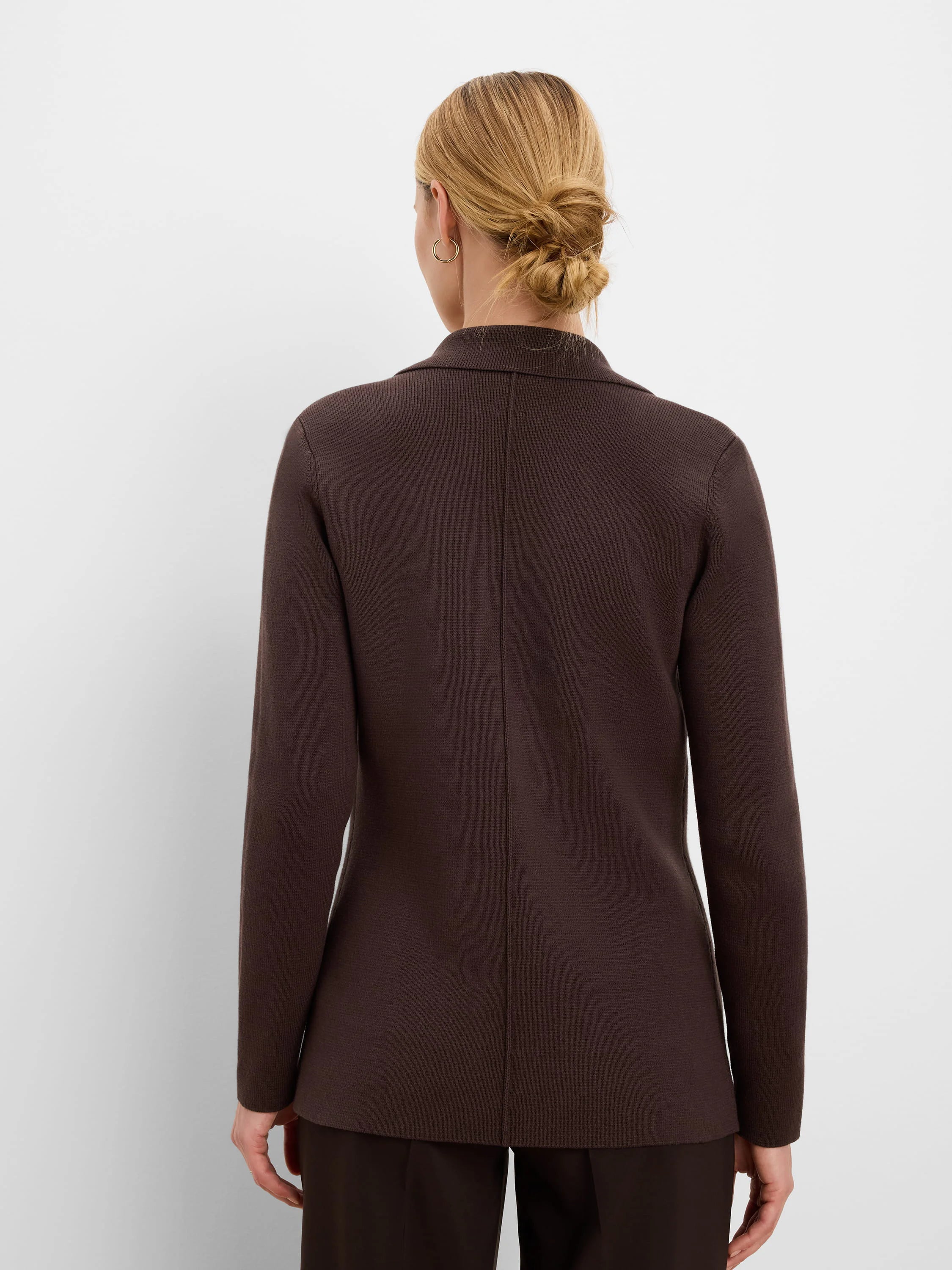 Dark brown knit blazer with a collar and center back seam, worn by a woman facing away.