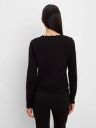 Black long-sleeved sweater, back view. Features a ruffled neckline and ruffled cuffs.
