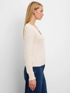 Cream Henley sweater with ruffle trim on the neckline and cuffs.