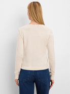 Cream long-sleeve sweater with ruffled neckline and cuffs, modeled from behind.