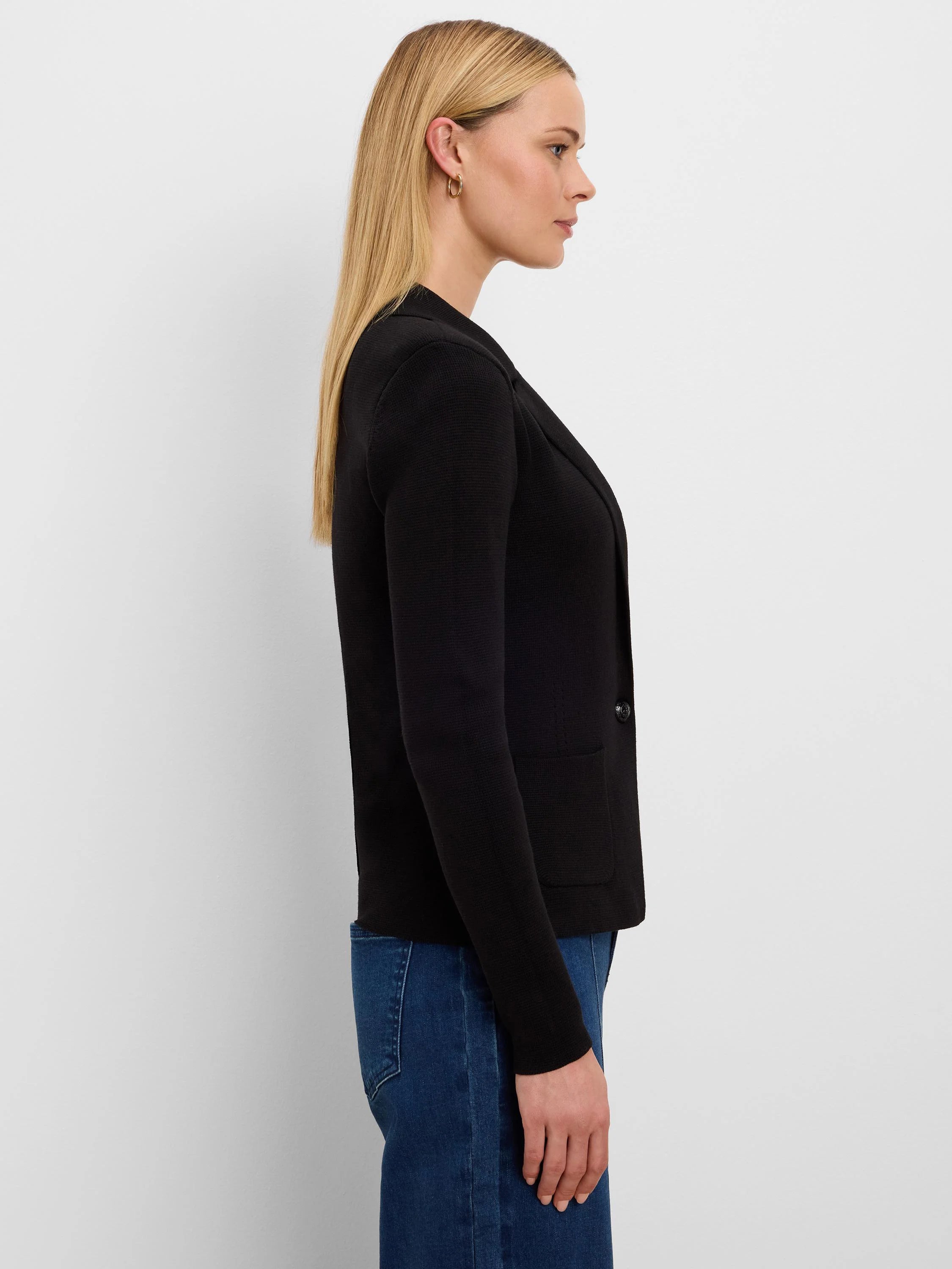 Black knit tailored blazer with single button, two front pockets, worn by a woman in profile.