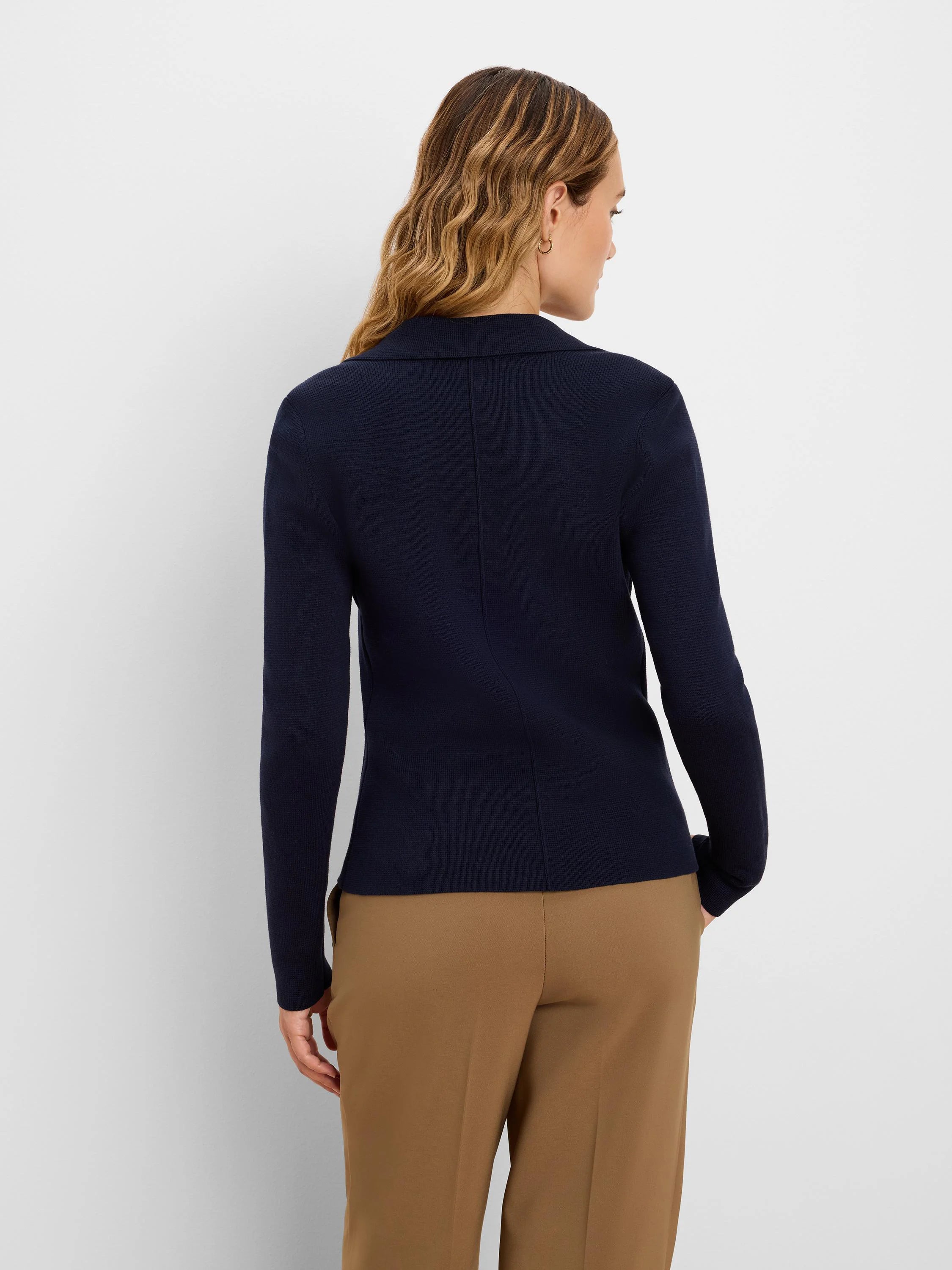 Navy knit tailored blazer, seen from behind. Features a notched collar, subtle ribbed texture, and a vertical back seam.
