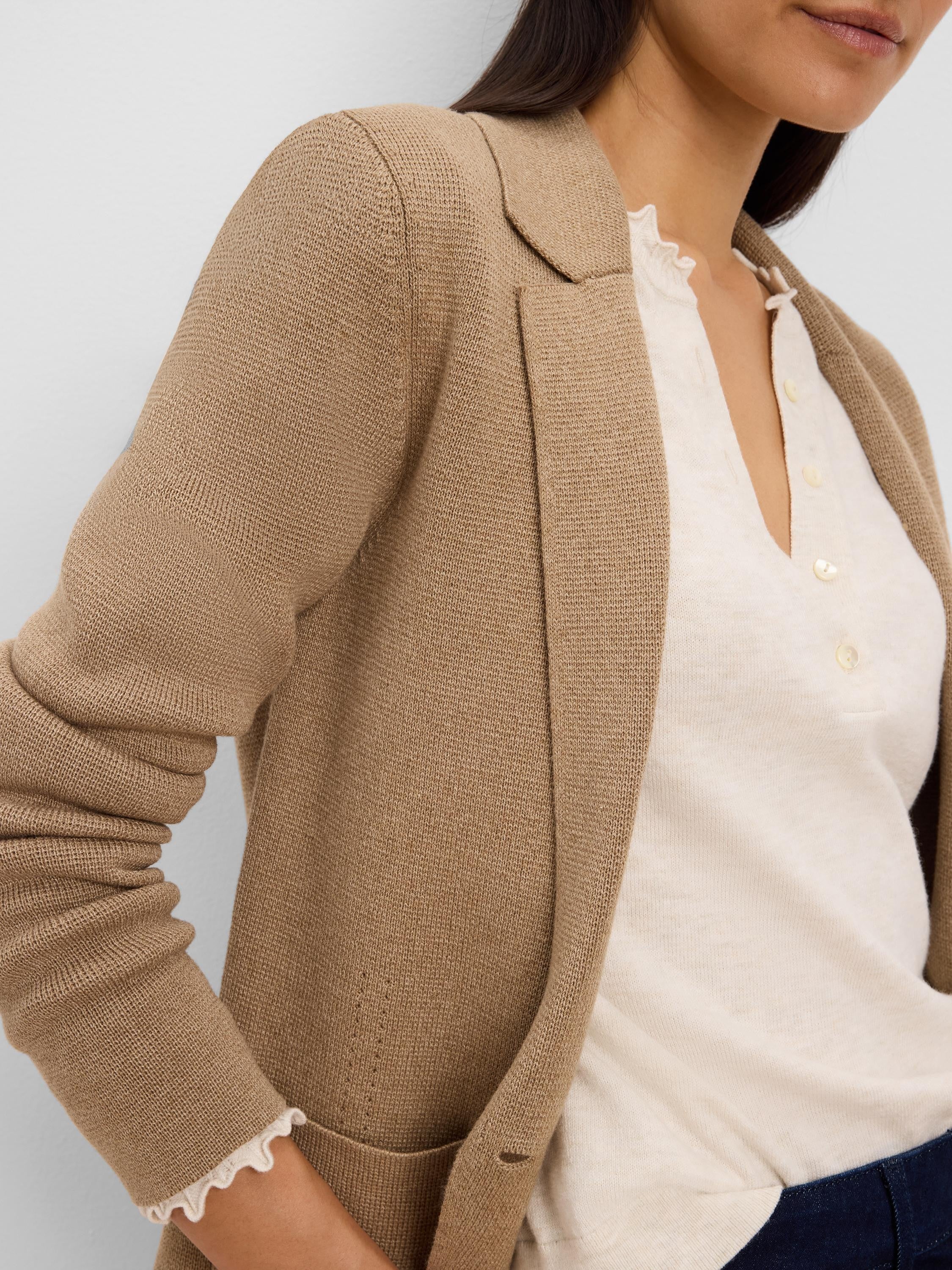 Camel knit tailored blazer with lapels and visible knit texture, worn over a cream shirt.
