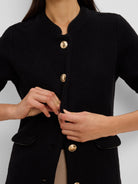 Textured black knit jacket with gold buttons, black trimmed stand collar with V-cutout, and trimmed pockets.