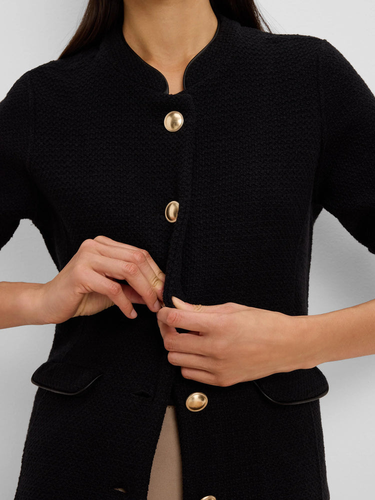 Textured black knit jacket with gold buttons, black trimmed stand collar with V-cutout, and trimmed pockets.