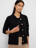 Black textured knit jacket, collarless, with gold buttons and black trimmed pockets.