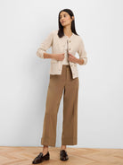 Cream weave knit jacket. Collarless, gold buttons, two flap pockets, and subtle trim.