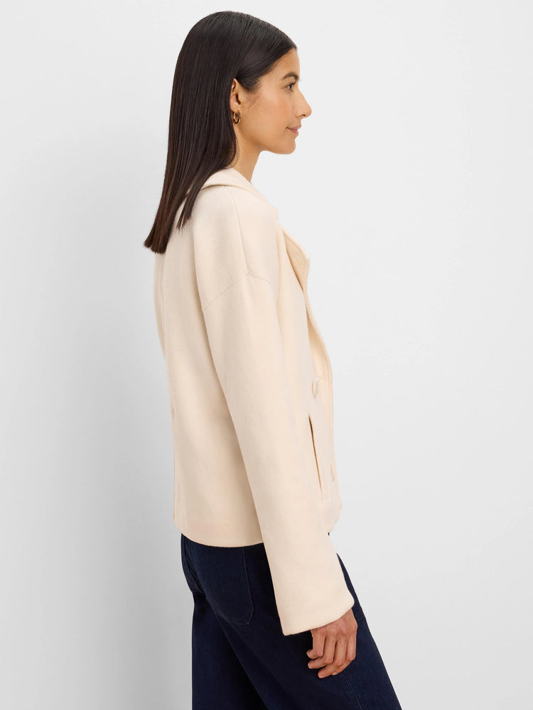 Cream knit jacket with a collar, two buttons, and front slit pockets, shown on a model.