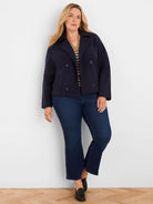 Cropped navy knit jacket with a collar, double-breasted button closure, and side pockets.