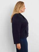 Dark blue knit jacket with collar, two buttons, and front pockets. Cropped fit.