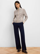 Beige knit jacket with dark swirl pattern, full gold zip, stand collar, and two buttoned pockets.