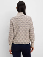 Beige knit jacket with dark grey interlocking ovals pattern. Ribbed turtleneck, cuffs, and hem.
