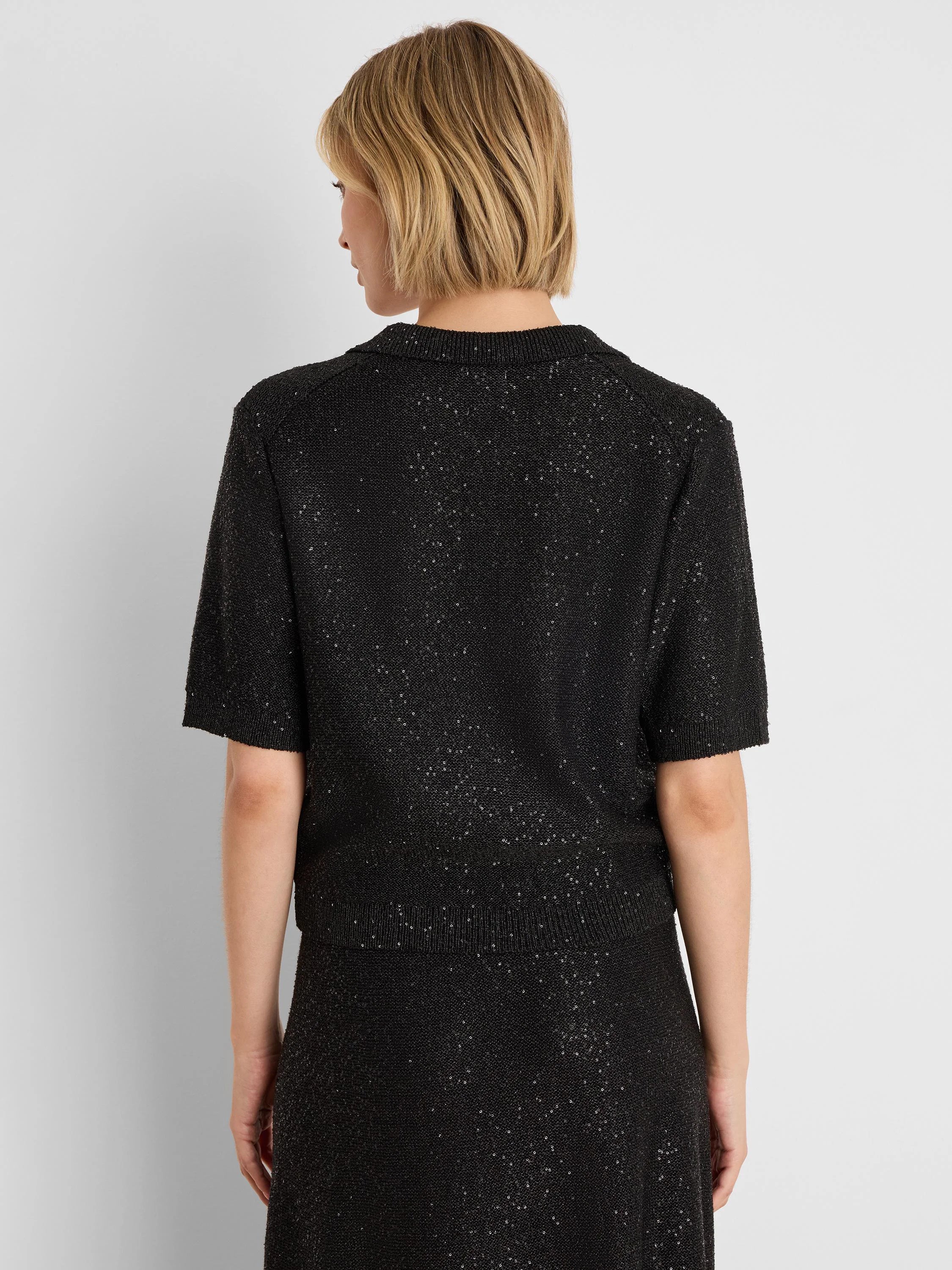 Black sequin polo sweater with short sleeves and ribbed collar, shown from the back.