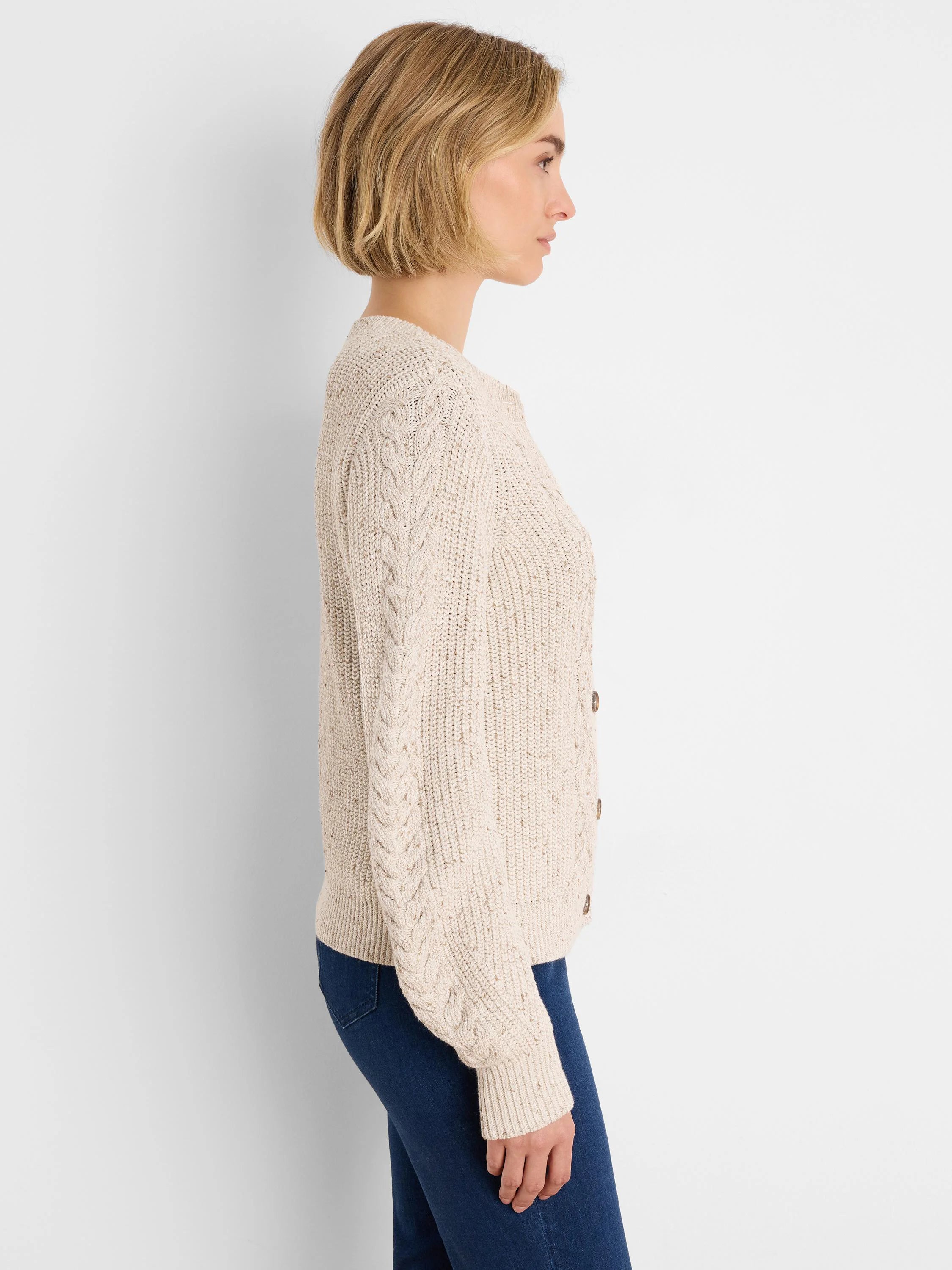 Cream flecked shaker cardigan with cable knit sleeves and dark brown buttons.