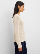 Cream loose-knit sweater with mixed diamond stitch patterns.