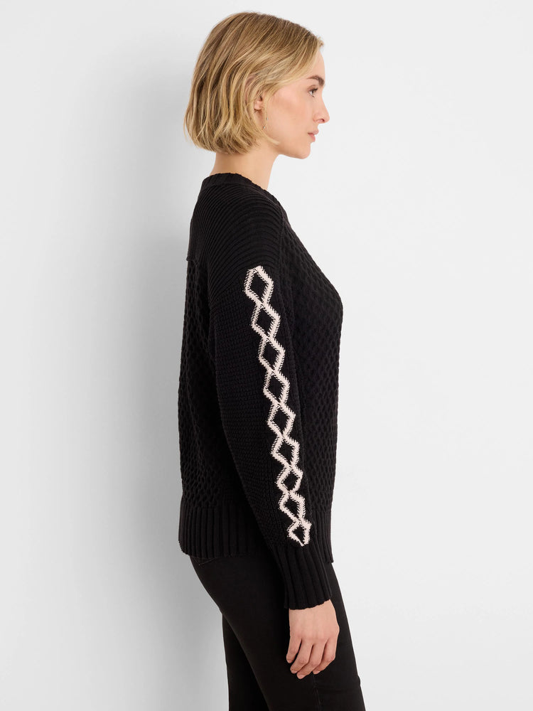 Black sweater with light-colored diamond pattern down the sleeves.