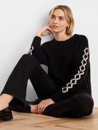 Black textured knit sweater with cream criss-cross diamond patterns running down the sleeves.