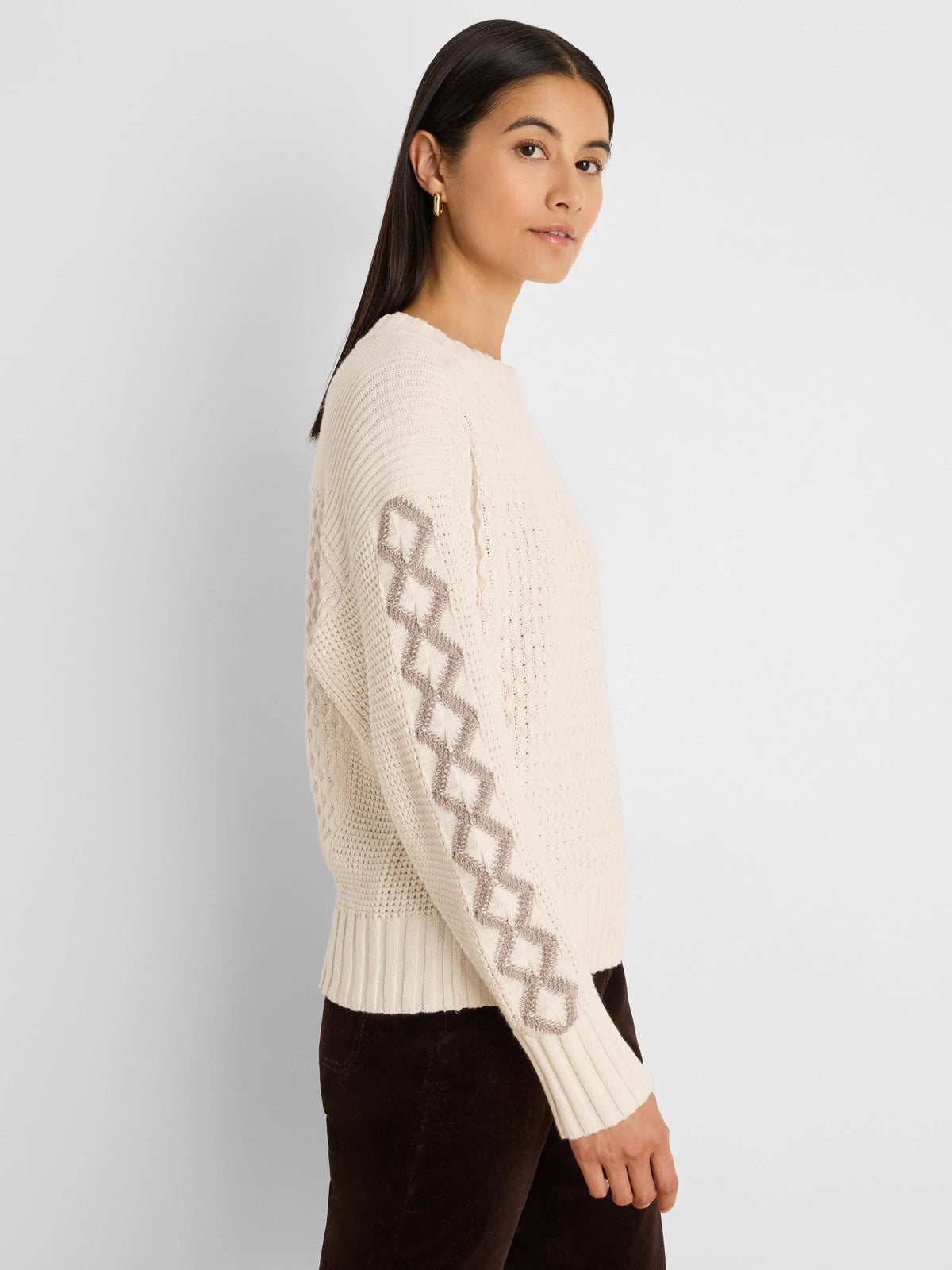Off-white knit sweater with taupe criss-cross diamond patterns on sleeves, ribbed cuffs and hem.