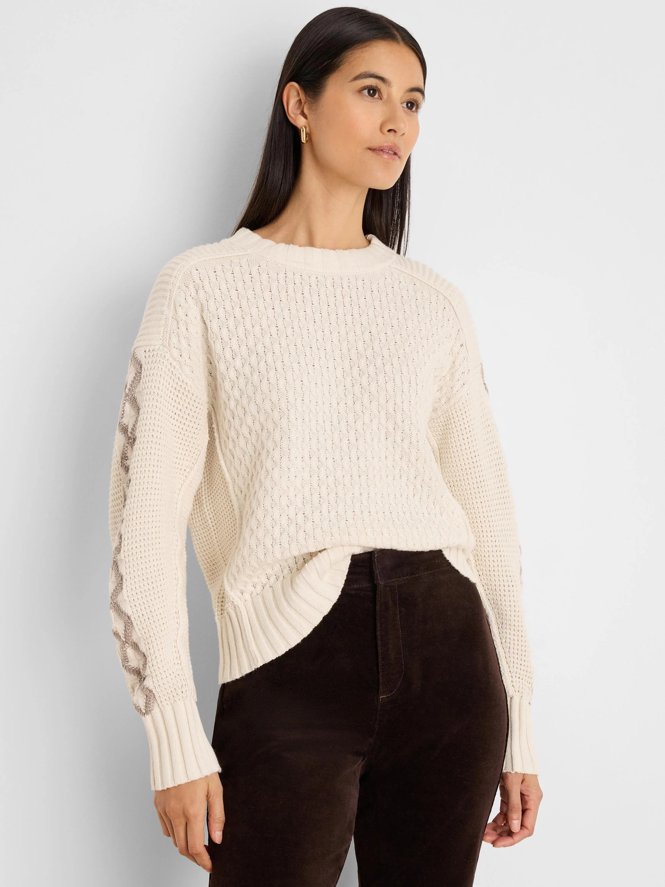 Cream sweater with textured knit body and taupe criss-cross pattern on sleeves. Ribbed cuffs and hem.