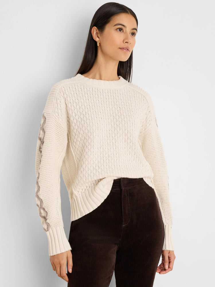 Cream sweater with textured knit body and taupe criss-cross pattern on sleeves. Ribbed cuffs and hem.